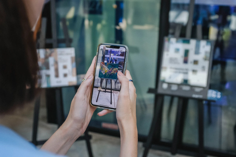 Exhibition visitor with a phone showing an artwork in the app