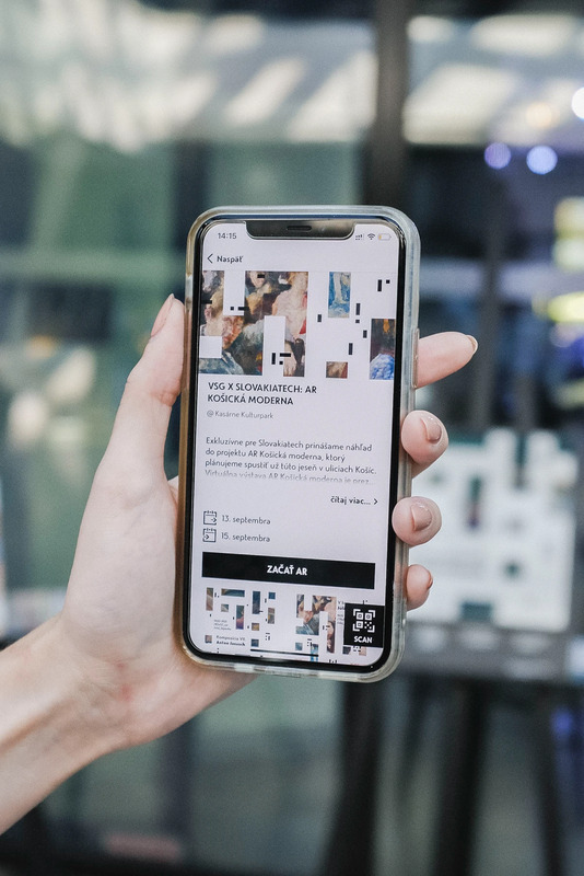 Visitor holding a phone showing artwork information in the app