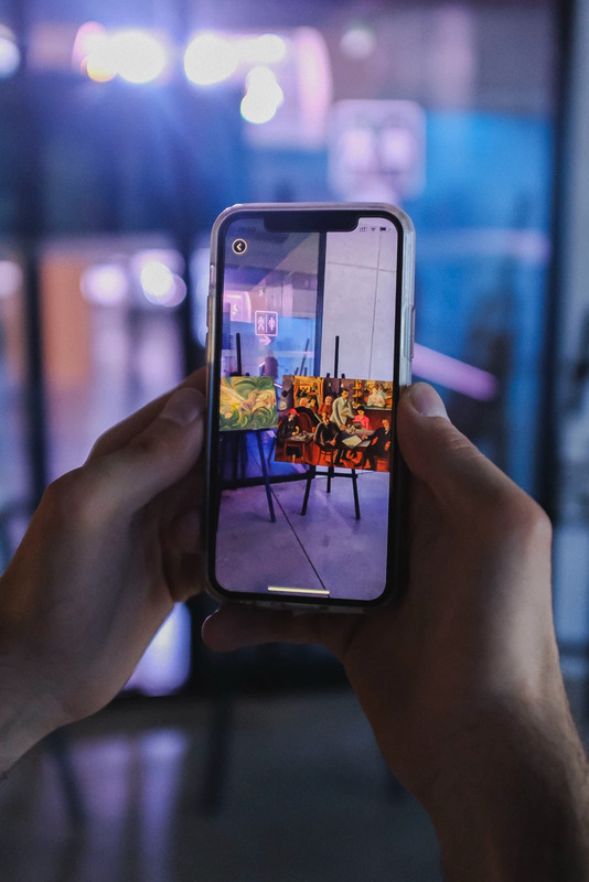 Exhibition visitor holding a phone showing an artwork in the app