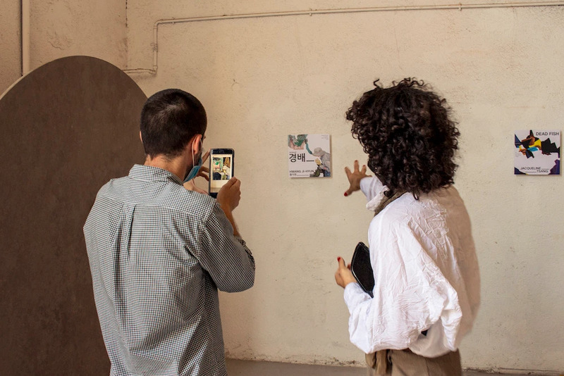 Exhibition visitors scan and point at an app marker on the gallery wall