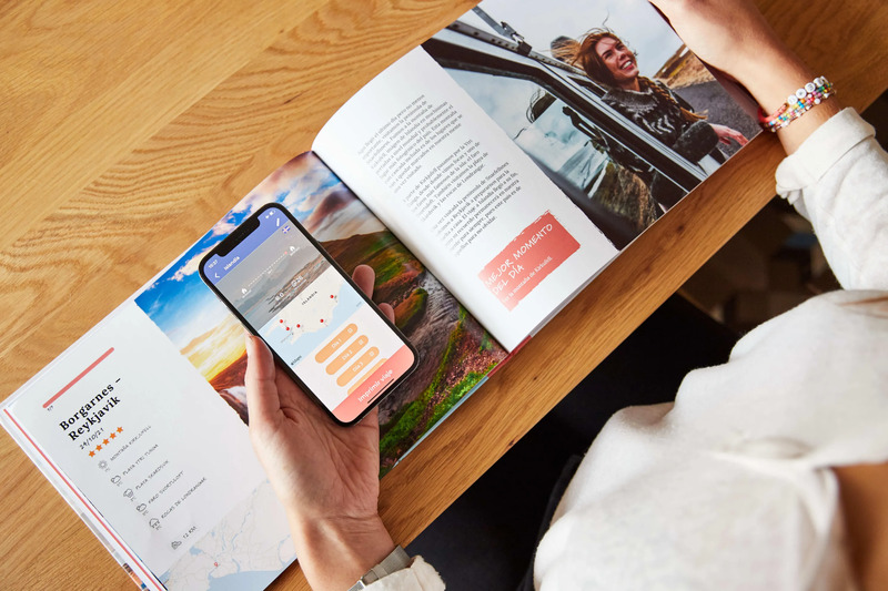51trips printed travel book next to a phone showing a trip entry in the app